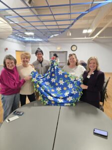 Rotarians showing off a blanket.